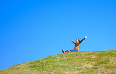 Wall Mural - Portrait of a little girl sitting on green grass