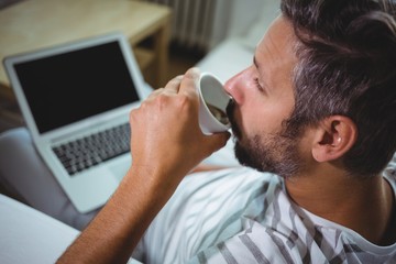 Poster - Man having coffee while using laptop