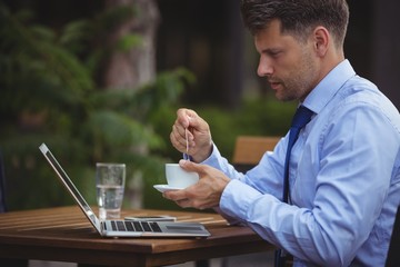 Aufkleber - Handsome businessman having tea while using laptop