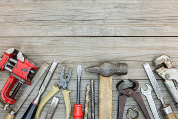 old rusty tool set of different instruments for house renovation and construction on grey wood board background