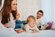 © AS Photo Family - Mother and father with baby boy lying on white bed with garland