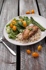 Dinner plate of lemon pepper mustard chicken with brown rice, Italian garden salad, and asparagus cooked in avocado oil on weathered barn wood table