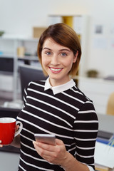 Poster - frau im büro mit handy und einer tasse tee