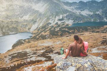 A young couple sitting on a rock and enjoying the view