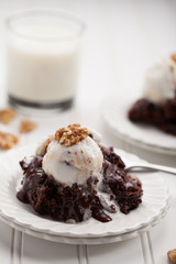 Hot fudge chocolate cake topped with caramel chocolate vanilla ice cream and walnuts served with a cup of milk