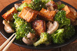 Vegetarian food: fried tofu with broccoli, mushrooms and sesame close-up. horizontal
