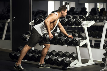 Wall Mural - Well built strong man holding a dumbbell