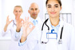 © rogerphoto - Happy doctor woman  with medical staff at the hospital. Thumbs up and Ok sign!