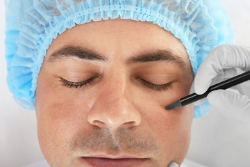 Wall Mural - Plastic surgery concept. Hand in glove marking male face