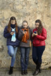 Internet and social networks replace live communication. Three girls together chat using their smartphones outdoor - vertical