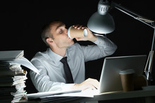 Businessman Drinking Coffee At Desk At Night
