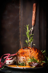 Roasted Christmas ham with fork at wooden background, side view