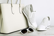 White Ladies Handbag, Shoes And Sun Glasses On A Light Backgroun