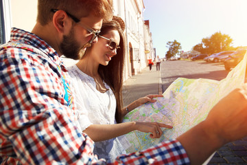 Happy couple walking outdoors sightseeing and holding map