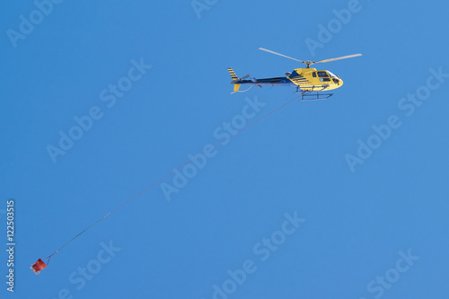 Fotografering Gelber Hubschrauber transportiert Betonkübel im Baustelleneinsatz