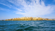 View From The Sea To The Ancient Fortress City Of Acre In Israel Against The Backdrop Of A Colorful Sky.