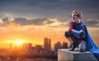 At sunset,little boy dressed as superhero watches over the city