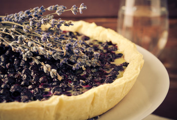 Bilberry, blueberry tart with lavender on white plate, wooden background