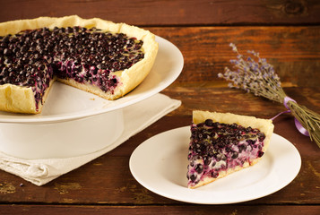 Bilberry, blueberry tart with lavender on white plate, wooden background