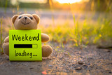 Fototapeta  - Happy Weekend on sticky note with teddy bear on nature background