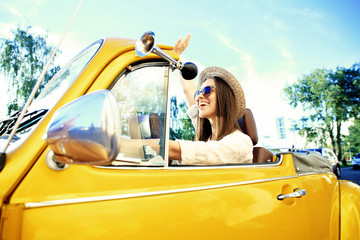 Portrait of Young girl driving cabriolet at sunset