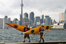 Couple Carrying Kayaks In Front Of  Toronto Skyline, Canada