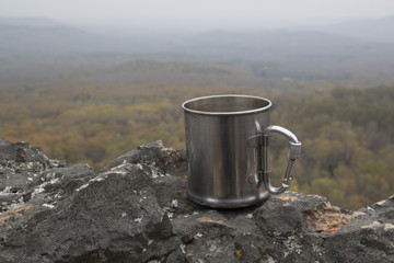 A mug in the mountains on the background of the valley observed from the top