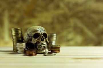 Human skull ,Pile thai coins of one bath on wood background.Conc