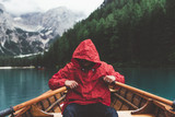 Fototapeta Sypialnia - Man with red raincoat rowing a wood boat on Braies lake	
