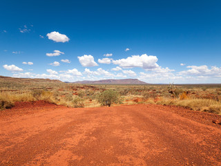 a wide shot of the harsh arid red landscape of the australian outback bush, with a vivid blue sky ba