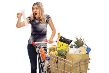 Wall Mural - Shocked young woman looking at a store receipt