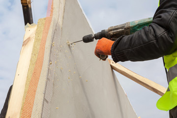 Wall Mural - Roofer builder worker use drill to make a hole in structural Insulated Panel