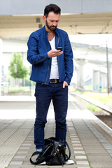 Wall Mural - Man using mobile phone at train station