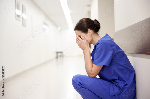 Fotografía sad or crying female nurse at hospital corridor