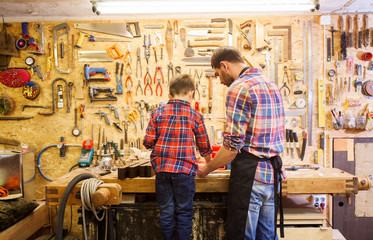 father and little son with wood plank at workshop