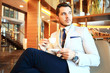 © opolja - Portrait of handsome successful man drink coffee sitting in coffee shop, business man having breakfast at hotel lobby.