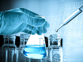 Wall Mural - flask in scientist hand with laboratory glassware background