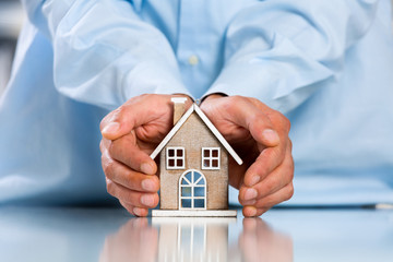 Male hands saving Miniature House