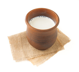 Wall Mural - Milk in a clay mug on burlap napkin. Top view. Isolated.