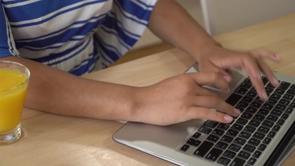 Poster - woman's hands computing on computer. woman sitting at the wooden desk with pc and glass with drink orange juice in the office. Male sharing information via internet or chatting in social net or