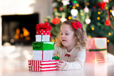 Fototapeta Na ścianę - Little girl opening presents on Christmas morning