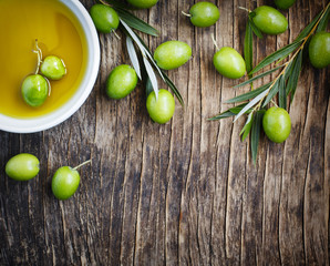 Wall Mural - Fresh green olives with leaves and olive oil on wooden backgroun