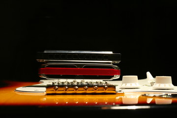 Vintage electric guitar with harmonica on black background