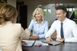 © sepy - Handshake. Shot of an investment manager shaking hands with smiling woman while consulting with middle aged couple about financial savings.