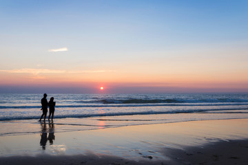 Silhouettes of a couple enjoying the sunset on the atlantic ocean, Lacanau France