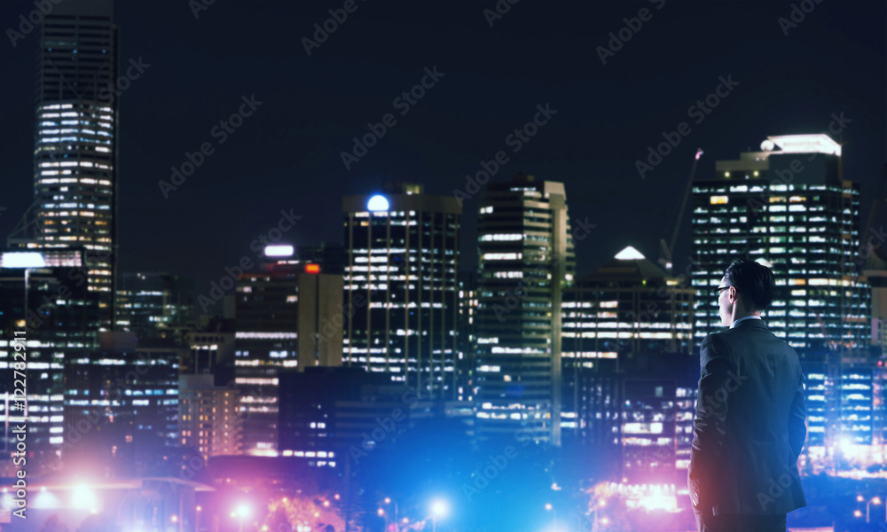 Businessman viewing night glowing city - obrazy, fototapety, plakaty 