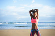 © Dirima - Fitness woman stretching triceps and back at the beach. Black female athlete working out outdoor against the sea.