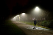 Einsame Person geht auf beleuchteter Straße in der dunklen Nacht