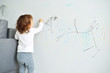 © galina_d - Curly cute little baby girl drawing with crayon color on the wall. Works of child