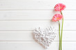Two pink gerber daisy flowers on  wooden backgraund. Gerbera and decorative heart. Flat lay, top view